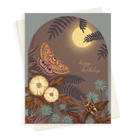 Birthday greeting card featuring illustrated moths, flowers, and ferns under a full moon on a brown background. Illustrated by Lisel Ashlock.