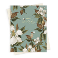 Birthday greeting card with white magnolia flowers, green leaves, and honeybees on muted teal background. Illustrated by Lisel Ashlock.