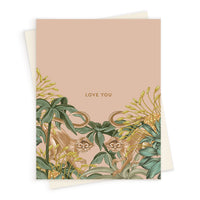 A "Love You" greeting card featuring illustrated monkeys among tropical foliage on a pink background. Illustrated by Lisel Ashlock.