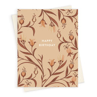 Greeting card with "Happy Birthday" text centered on a beige background filled with hand-drawn peach-colored flowers and brown leaves. Illustrated by Lisel Ashlock.