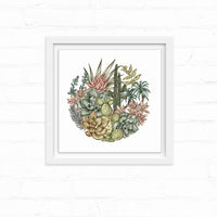 Circular botanical illustration of desert succulents and cacti with pink flowers in a white frame on shiplap. Illustrated by Lisel Ashlock.