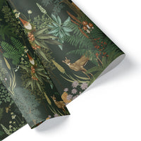 Rolled gift wrap featuring woodland animals, ferns, and botanical illustrations on a dark green background. Illustrated by Lisel Ashlock.