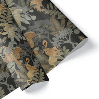 Rolled gift wrap featuring botanical illustrations with birds, flowers, and foliage in gold, gray, and cream on dark background. Illustrated by Lisel Ashlock.