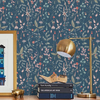 A wooden desk against indigo floral wallpaper with gold lamp, books, and decorative items. Illustrated by Lisel Ashlock.