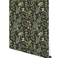 Dark botanical wallpaper featuring ferns, wildflowers, birds, and insects in greens, golds, and blush tones. Illustrated by Lisel Ashlock.
