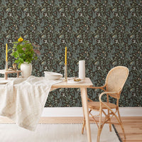 Dining room with Secret Garden Wallpaper in sable featuring ferns and florals, natural wood furniture, and cream accents. Illustrated by Lisel Ashlock.