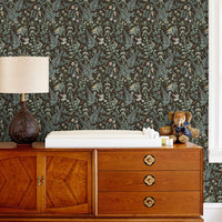 Secret Garden Wallpaper in sable featuring ferns and florals behind mid-century wooden dresser. Illustrated by Lisel Ashlock.