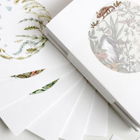 Opened greeting card featuring botanical illustrations of grains, plants, and wildlife with neutral tones. Illustrated by Lisel Ashlock.