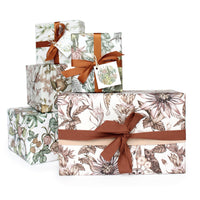 Stack of decorative gift boxes with botanical floral patterns in earth tones tied with rust-colored ribbons. Illustrated by Lisel Ashlock.