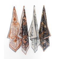 Four folded silk cotton scarves in earth tones featuring botanical and animal prints in orange, black, cream, and gold. Illustrated by Lisel Ashlock.