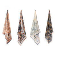 Four folded silk cotton scarves in earth tones displaying botanical and animal patterns in tan, cream, black and gold. Illustrated by Lisel Ashlock.