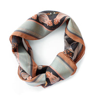 A folded moonstone silk cotton scarf featuring orange flowers and dark striped patterns. Illustrated by Lisel Ashlock.